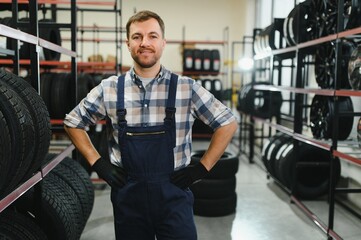 Portrait of smiling warehouse worker standing by the pile of new car tires