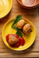 A top down view of a yellow plate of polenta roasted potatoes in marinara sauce.