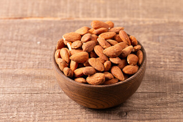 Raw peeled almonds in brown wooden bowl. Organic food concept. 