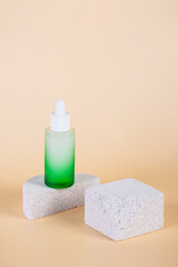 Green glass cosmetic bottle, Skin care or sunscreen cosmetic with stylish props on cream background.