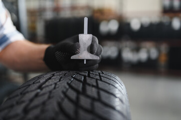 Mechanic measuring tire tread depth in automobile service centre