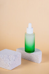 Green glass cosmetic bottle, Skin care or sunscreen cosmetic with stylish props on cream background.