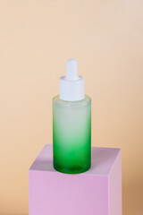 Green glass cosmetic bottle, Skin care or sunscreen cosmetic with stylish props on cream background.