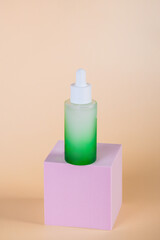 Green glass cosmetic bottle, Skin care or sunscreen cosmetic with stylish props on cream background.