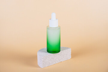 Green glass cosmetic bottle, Skin care or sunscreen cosmetic with stylish props on cream background.