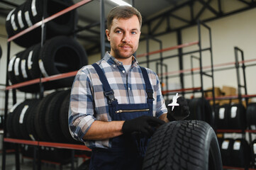Professional worker with tire. Man is in the tire fitting car service