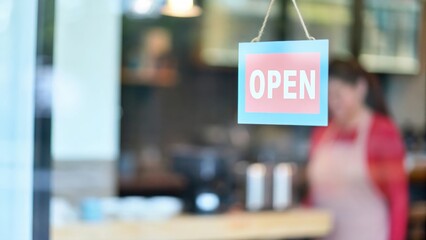 Blurred caf&eacute; interior behind glass door with &ldquo;Open&rdquo; sign inviting customers inside
