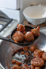 A view of a pile of grape jelly meatballs in a ladle.