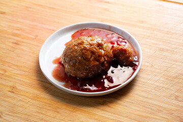 A view of a large meatball in grape jelly sauce.