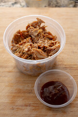 A view of a plastic container of crockpot BBQ chicken.