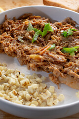 A view of a plate of pulled chicken, topped with scallion.