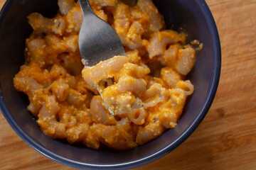 A top down view of a fork grabbing some butternut squash mac n cheese.