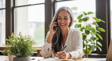 Professional woman working from home talking on her phone while writing in a notebook