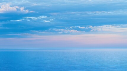 Obraz premium Calm blue sea meets the horizon under a soft pastel sky, creating a serene seascape