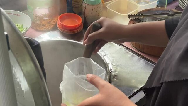 Packing Indonesian soto &mdash; hot, savory soup carefully wrapped for takeaway, capturing the flavors of street food culture and local comfort meals. June 2, 2025 - Karet, Indonesia