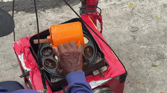 Street vendor preparing kue cubit &mdash; a popular Indonesian mini pancake snack cooked fresh on the roadside, loved for its soft texture and nostalgic flavor. Karet, Indonesia - June 25, 2025