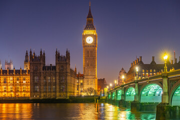 Fototapeta premium Stunning view of Big Ben and the Houses of Parliament bathed in golden lights at night. Westminster Bridge is illuminated, reflecting the vibrant atmosphere of London.