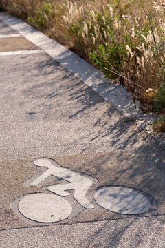 Urban bicycle path symbol on textured concrete sidewalk in sunlight, representing urban mobility, sustainable transportation, and infrastructure as integral parts of contemporary travel