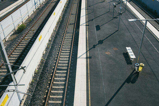 Empty railway platforms with parallel tracks under bright daylight, symbolizing urban travel, public transportation networks, and the anticipation of journeys in contemporary travel imagery