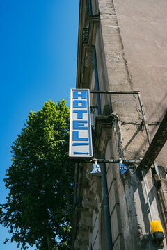 Vertical hotel sign on classic urban building facade under blue sky, symbolizing city travel, affordable accommodation, and the visual language of travel destinations in modern urban journeys