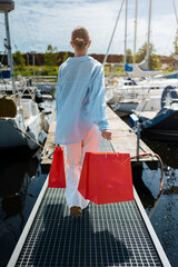Young female holding a red shopping bags during sunny day with blue sky background