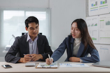 Two business professionals collaborate on financial analysis, reviewing charts and graphs in a...