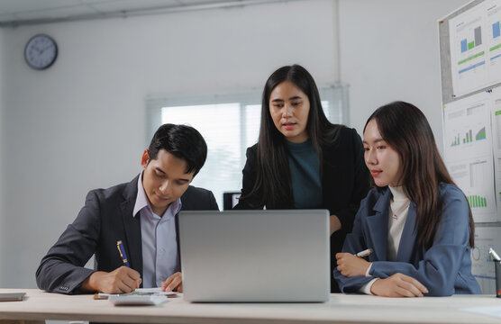 Diverse team engaged in a business meeting, discussing strategies and analyzing data on a laptop in a modern office setting - Powered by Adobe