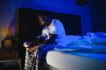 Bad Sleep. Portrait Of Black Guy Waking Up At Night Sitting In Bed In Bedroom At Home. Tired Man Having Headache And Insomnia Problem, Can't Fall Asleep. Sleeplessness Concept