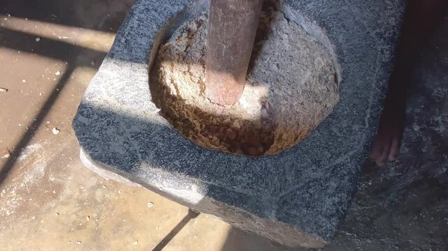 jarak dekat, seorang pria yang sedang menumbuk, dengan lesung batu dan kayu tradisional