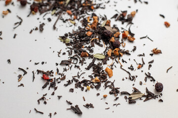 Scattered tea with dried fruit slices and cranberry leaves. Dried tea leaves with candied fruits on...
