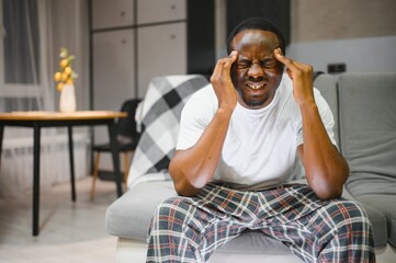 Closeup of young african american man suffering from headache at home, touching his temples....