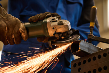 Worker Using Angle Grinder on Metal to Produce Sparks in Industrial Workshop