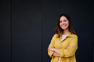 Confident Woman Smiling in Yellow Jacket Posing Against Dark Background
