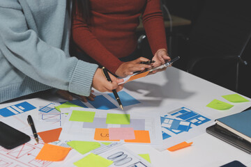 UX UI designer testing prototype on a phone, discussing and brainstorming on wireframes for a...