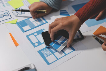 UX UI designer testing prototype on a phone, discussing and brainstorming on wireframes for a...