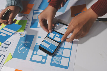 UX UI designer testing prototype on a phone, discussing and brainstorming on wireframes for a...