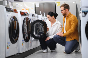 Couple choosing wasing machine at electronics store
