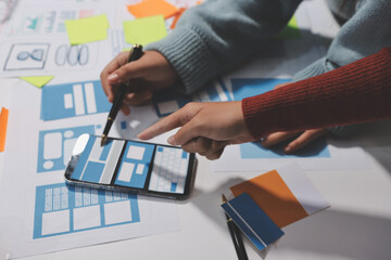 UX UI designer testing prototype on a phone, discussing and brainstorming on wireframes for a...