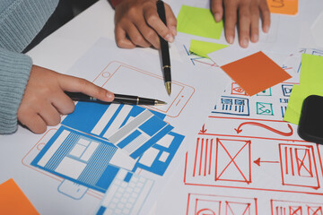 UX UI designer testing prototype on a phone, discussing and brainstorming on wireframes for a...