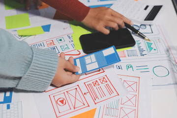 UX UI designer testing prototype on a phone, discussing and brainstorming on wireframes for a...