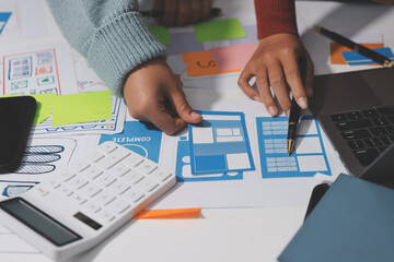 UX UI designer testing prototype on a phone, discussing and brainstorming on wireframes for a...