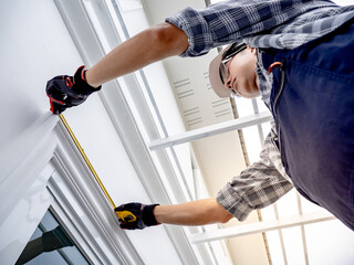 Home builder man checking the length of house wall. Asian male construction worker in protective...