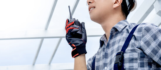 Half face of civil engineer man using walkie talkie to cooperate with the worker team while looking...