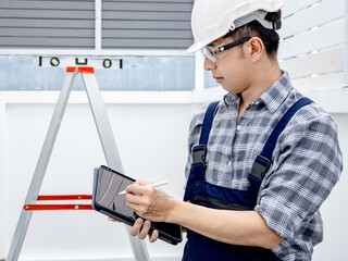 Confident building inspector man in protective workwear using digital tablet checking for house...