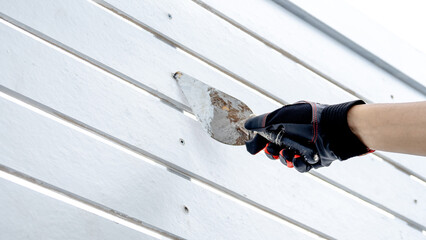 Male construction worker hand in protective glove using plastering trowel for bolt head grouting on...
