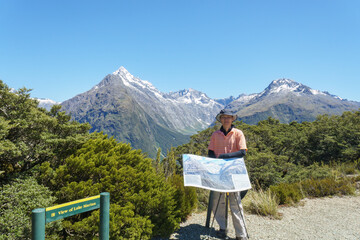 Naklejka premium Tourist posing for photos at the information board at Key Summit. Routeburn Track. South Island.