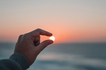Hand reaching for the sunset on a calm beach at dusk with soft waves in the background