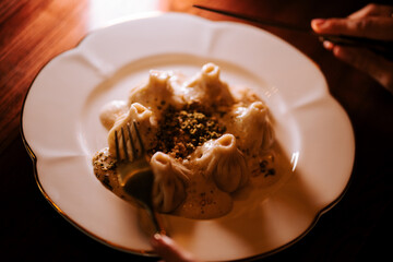 Enjoying khinkali served with rich sauce in a cozy dining setting