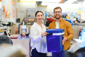A young couple buys a portable refrigerator in an electronics store