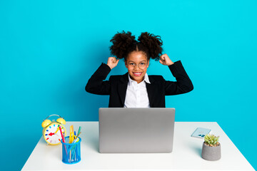 Confident young girl in stylish business attire at desk with laptop and a playful turquoise...